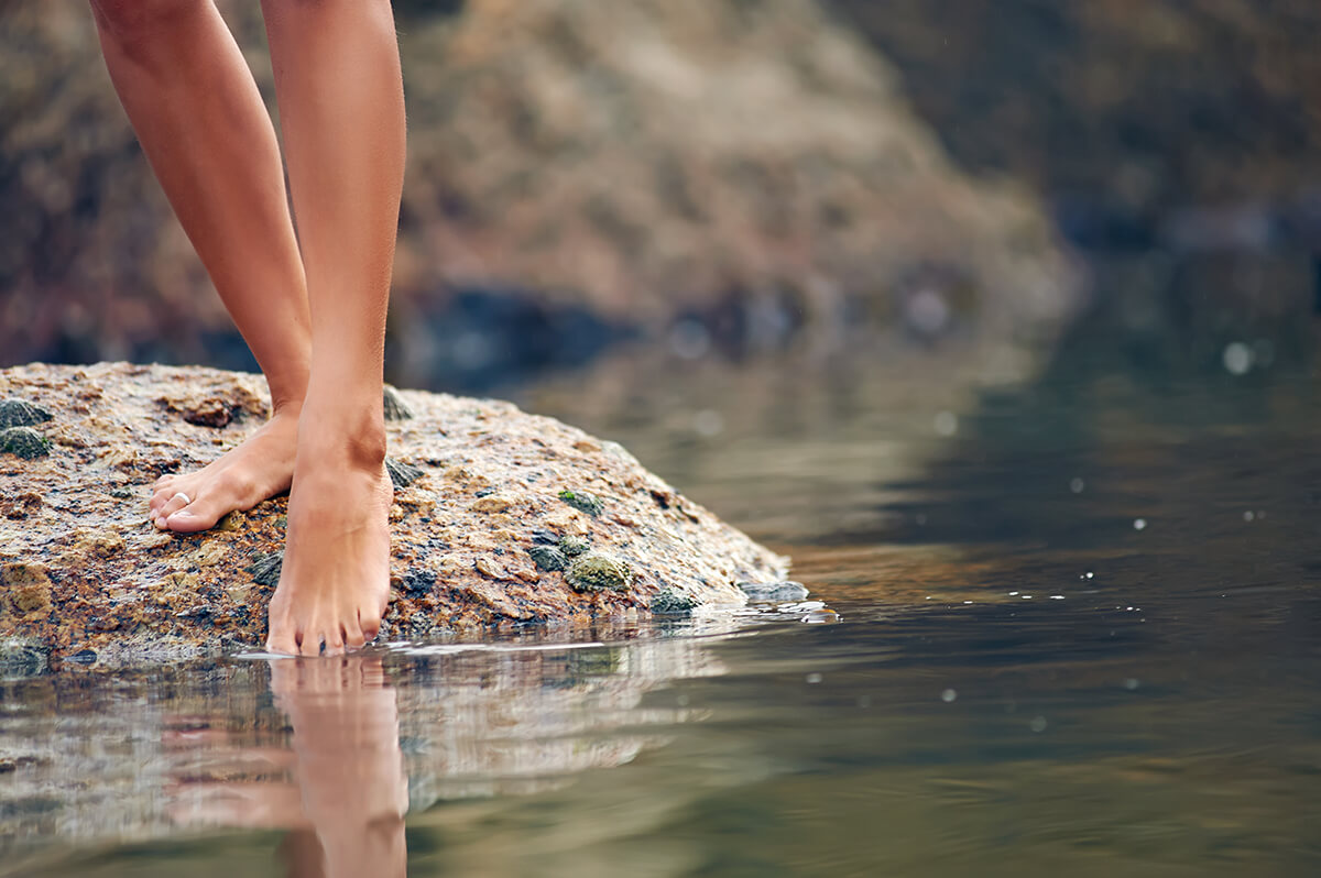 entrepreneur metaphore of person standing on a rock dipping their toes in water